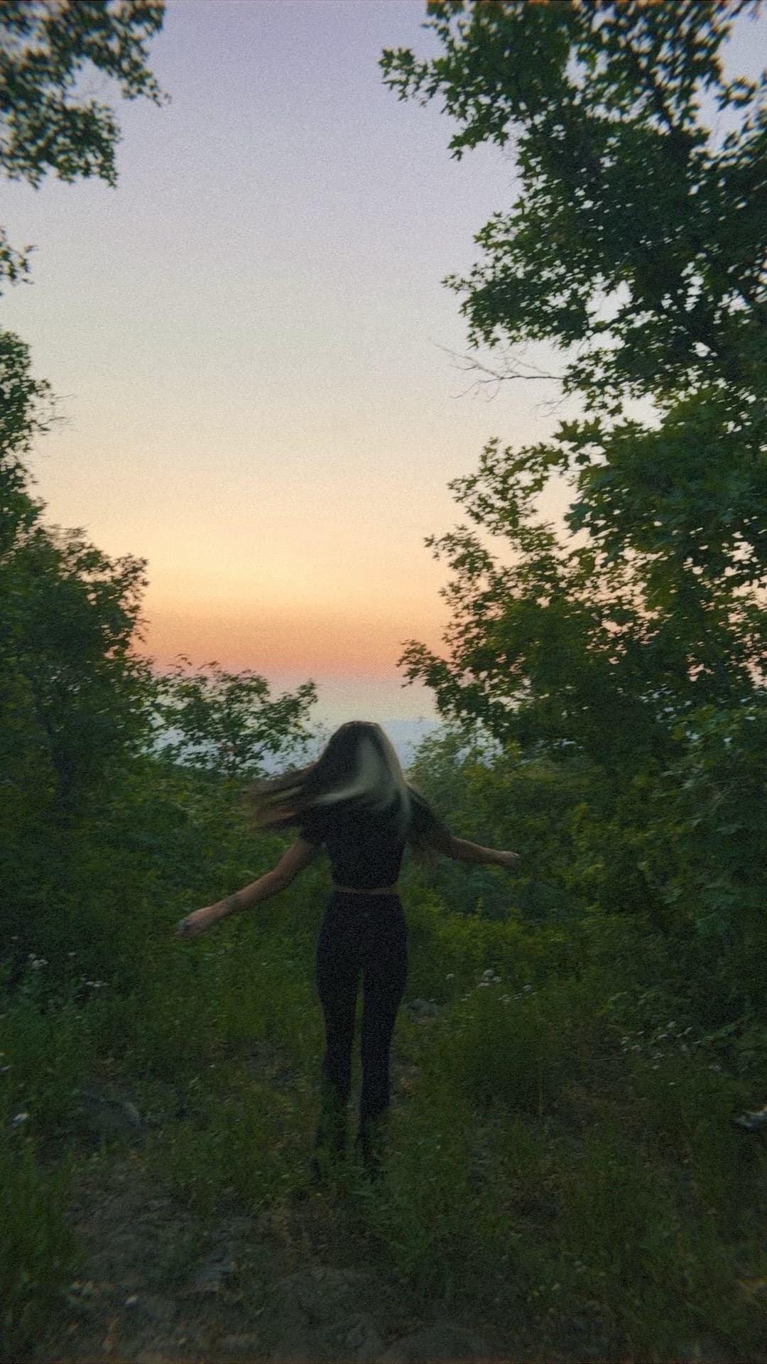 Blaire walking through the woods at twilight